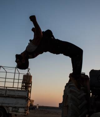 Backflip A fighter of the YPG doing a backflip from a vehicle.